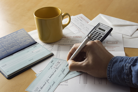 checkbook, papers and coffee cup on table, hand signing a check